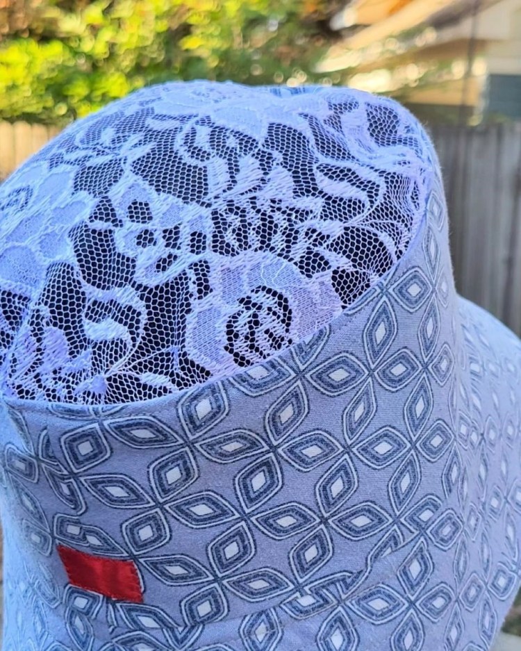 photo of bucket hat in geometric blue and white pattern with white lace crown and has a small red block of color on the back