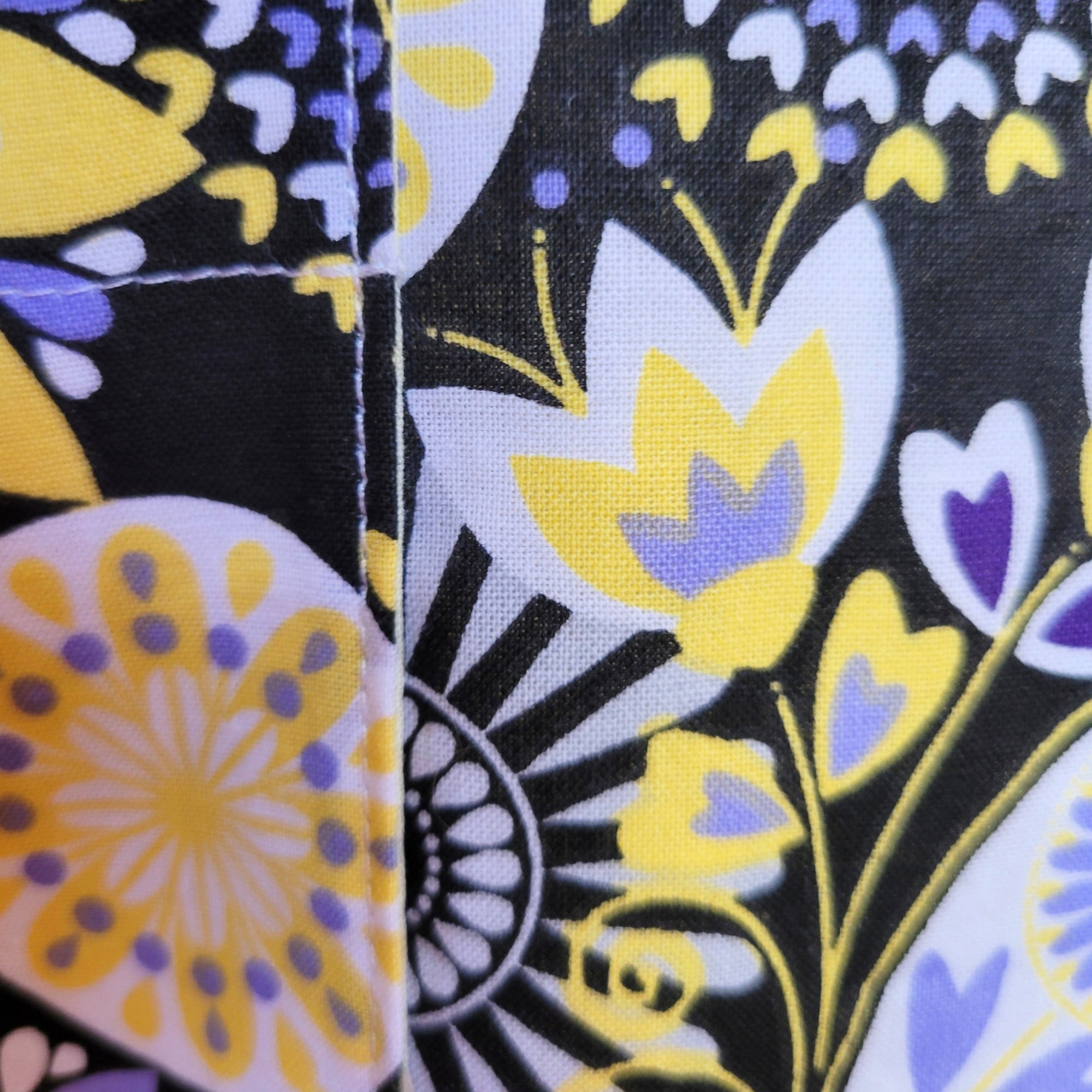 picture of black, yellow, periwinkle and white floral fabric highlighting stitch quality 100% cotton