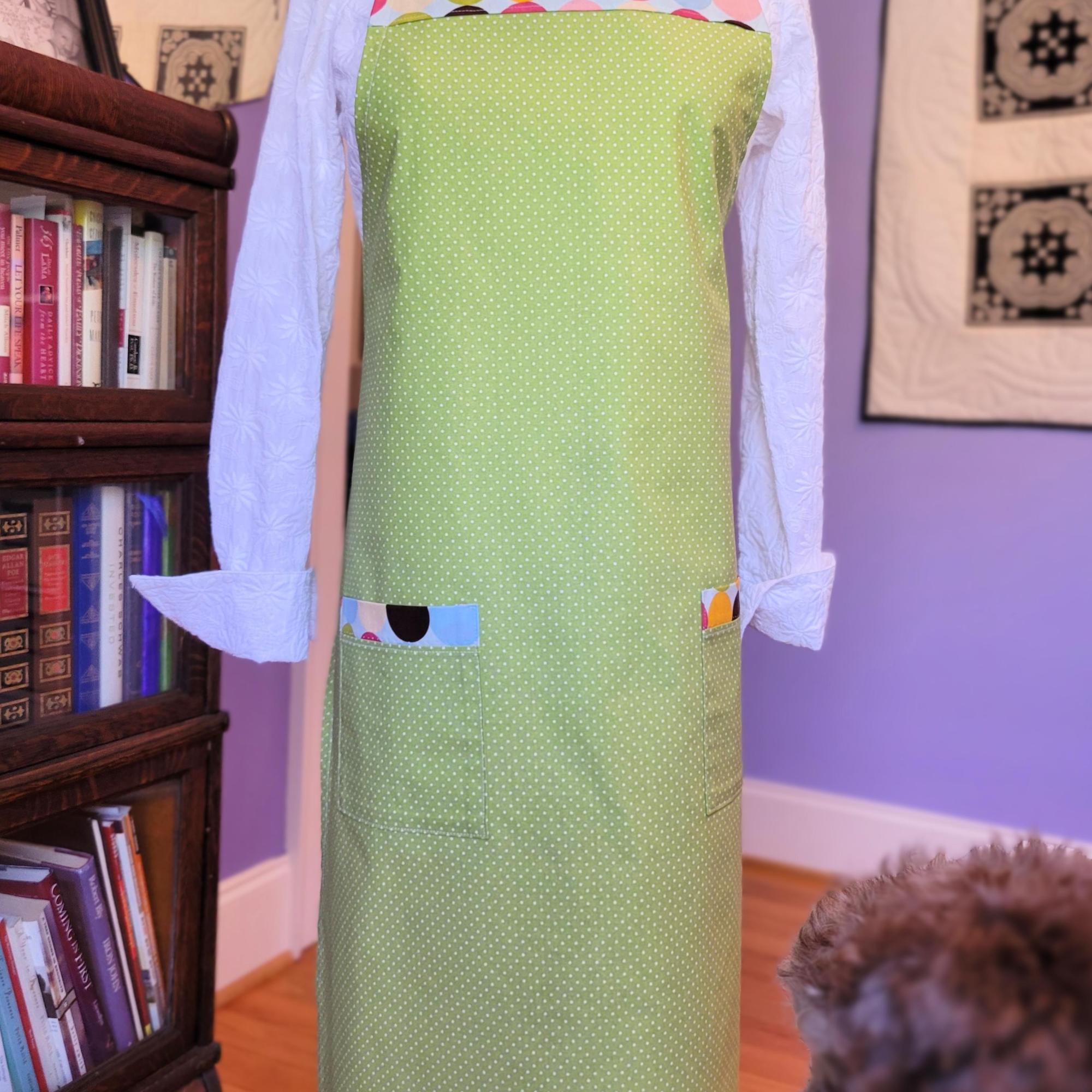 picture of lime green with small white poka dots apron with large multi-colored poka dots border on chest and 2 pockets