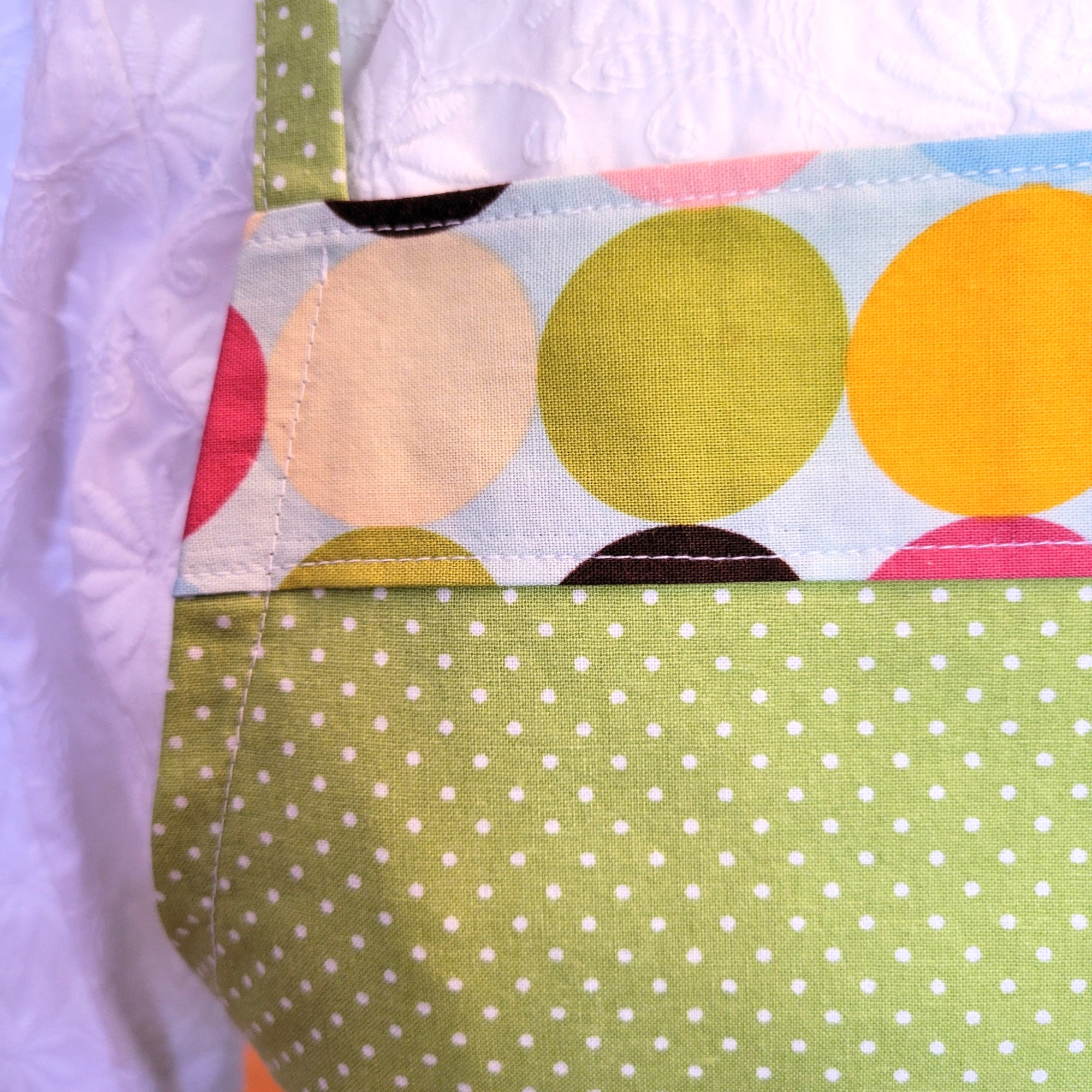 close-up photo of stitching of lime green with small white poka dot fabric and border of large multi-colored poka dots