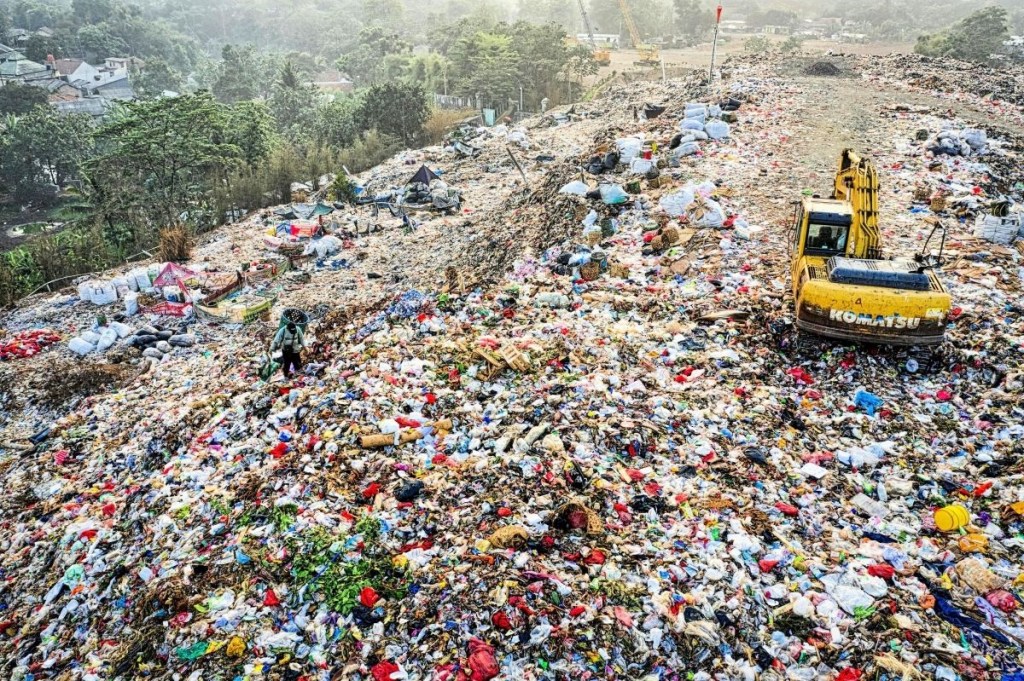 land polluted with plastics, textiles and food waste and has komuatsu machine moving mounds of garage